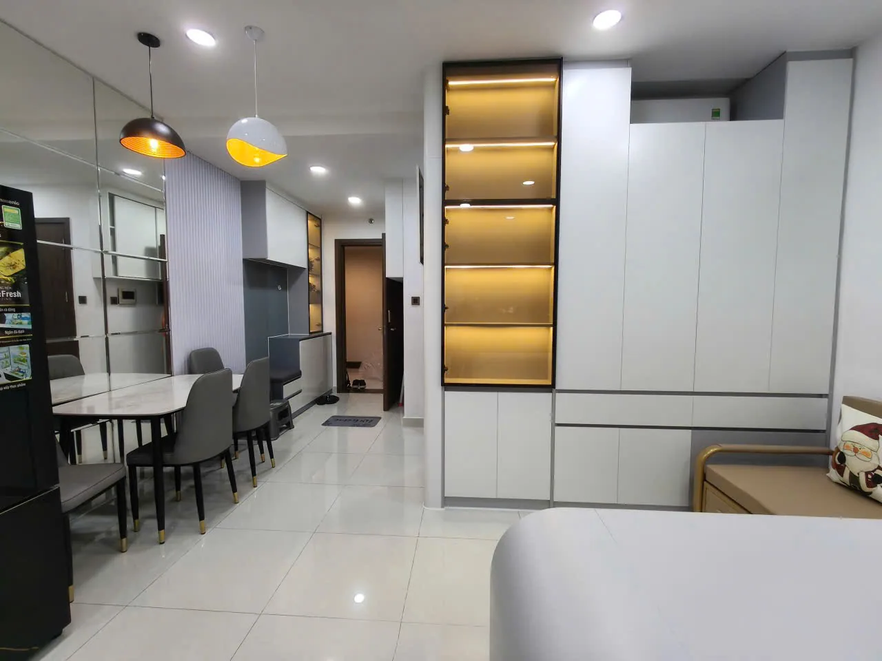 Góc nhìn tổng thể với hệ tủ, bàn ăn và kệ có đèn — Nội thất Vinhomes Grand Park